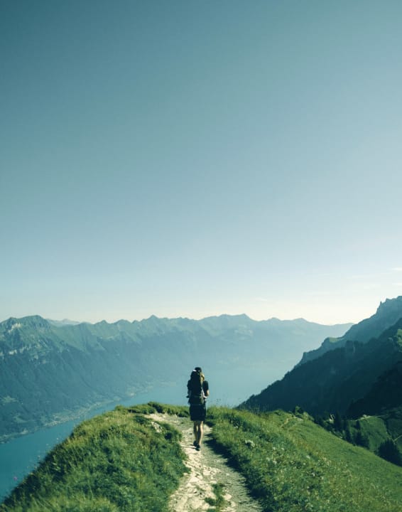 Hiker with a backpack walking along a mountain path with panoramic views