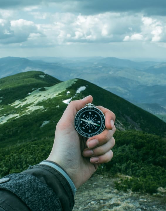 A man in the mountains looking at a compass